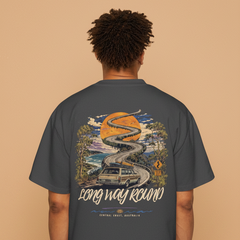 Long Way Round tee — wagon on a coastal road back print in orange on faded black, worn by a model